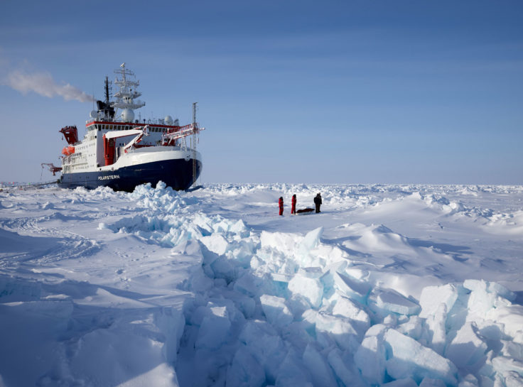 A large boat in the sea ice with people in the foreground