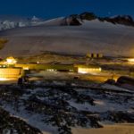 A research base lit up in an icy landscape in the dark