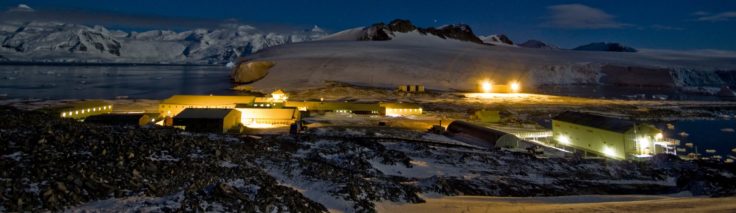 A research base lit up in an icy landscape in the dark