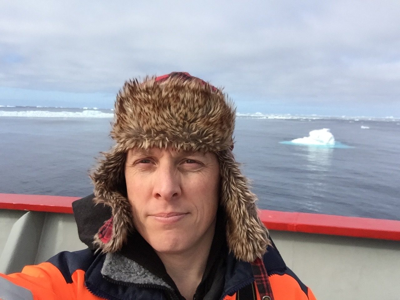 A man on a boat with icebergs and the sea in the background