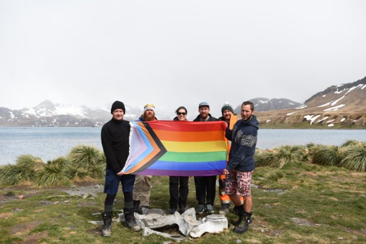 A team standing with a progress pride flag