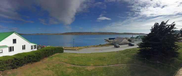 A body of water with grassy area in front of a building at Port Stanley, Falklands