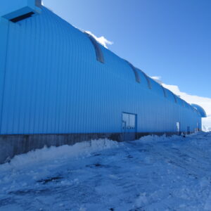 The side of a large blue building in a snowy environment