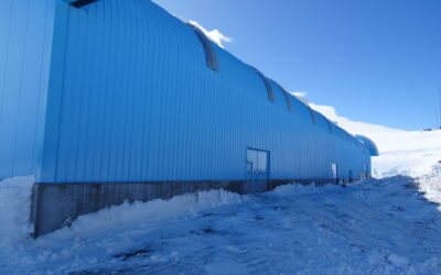 The side of a large blue building in a snowy environment