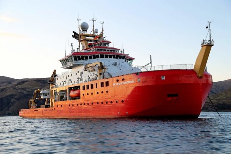 A large red ship in a large body of water