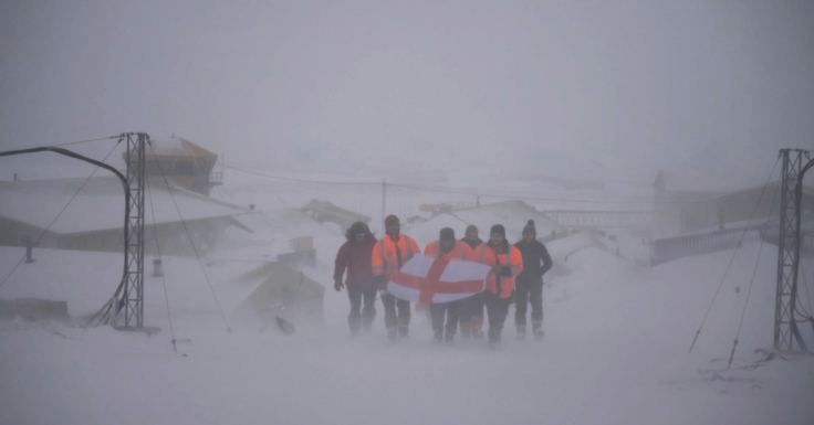 A group of people riding skis across snow covered ground