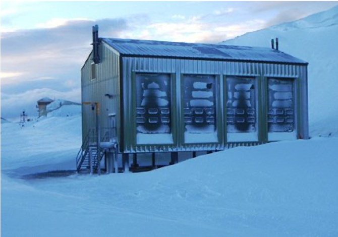 A close up of a snow covered slope with a laboratory building, with solar PV on the roof