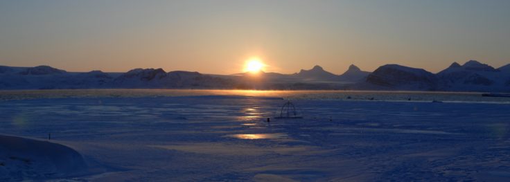 A sunset over a body of water with a mountain in the background