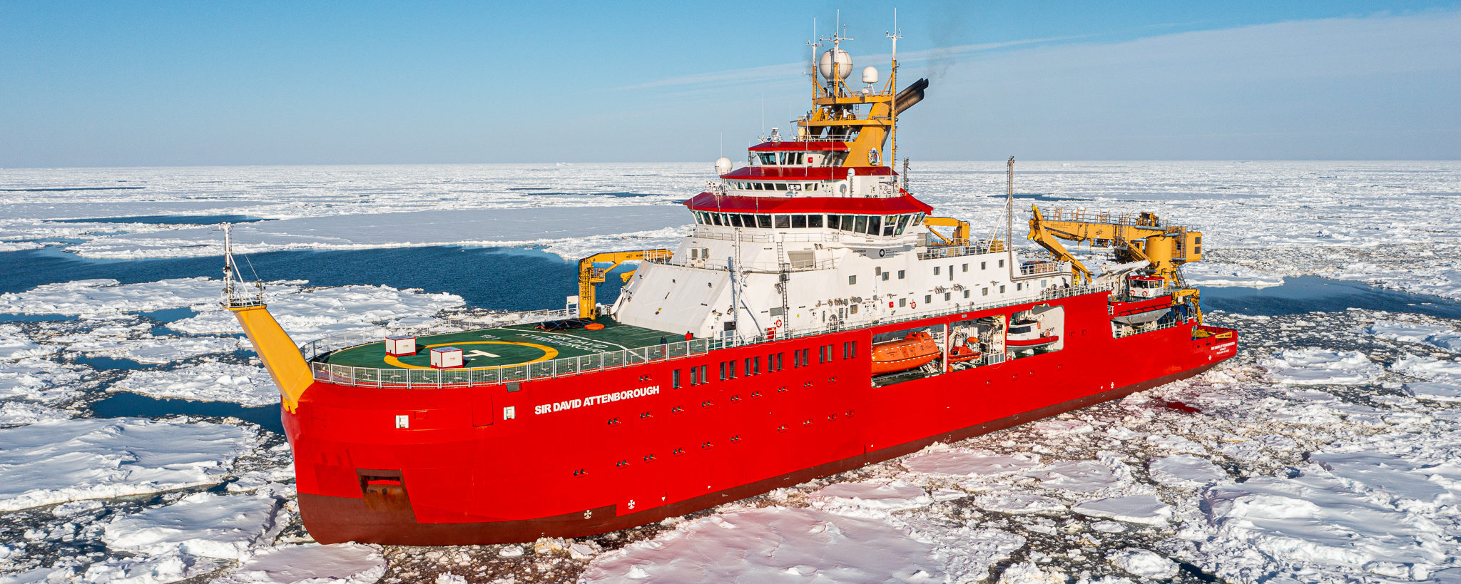 A large red ship in the ocean which is covered in bits of ice