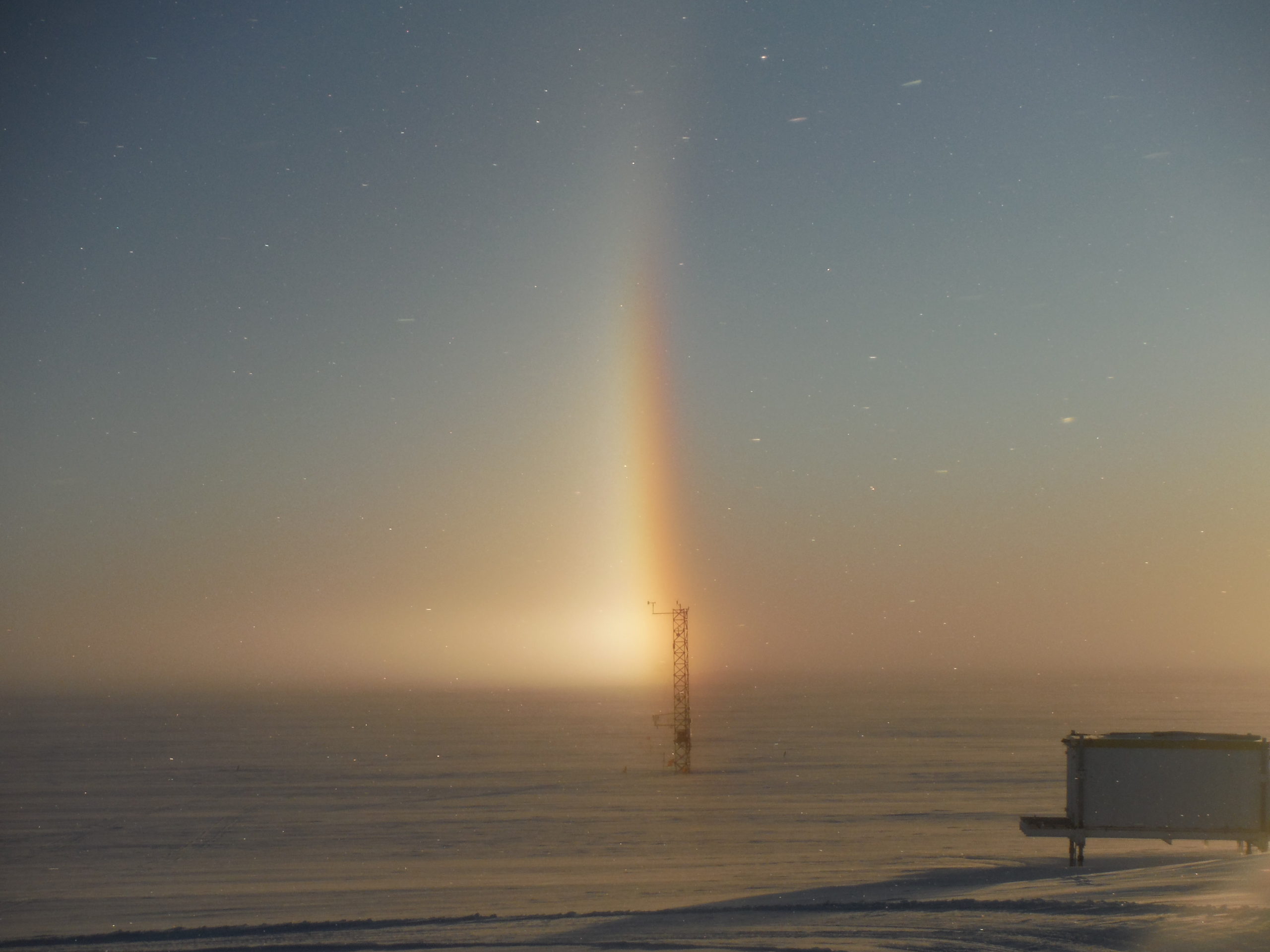 A vertical rainbow above a metal structure in the snow