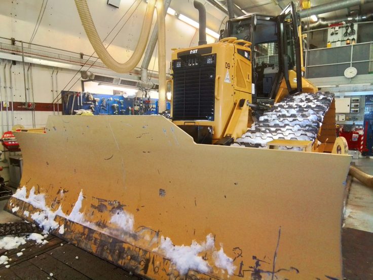 A large yellow bulldozer inside a workshop space.