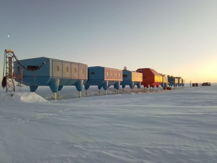 The long chain of building pods at Halley Research Station glow with reflected yellow light in a long Antarctic sunset.