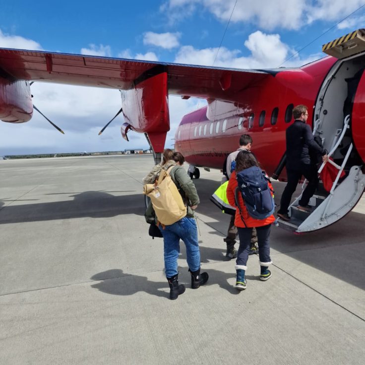 A group of people standing around a plane