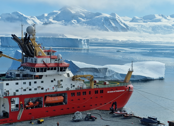 A large ship in a body of water with a mountain in the background