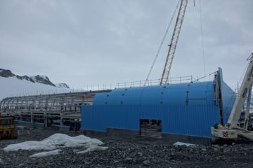 A blue building being constructed covered in snow