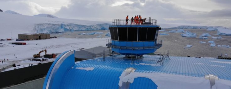 Construction team standing on top of operations tower of a new building in Antarctica