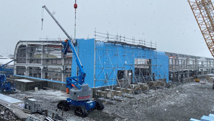 A large blue building being constructed in the snow