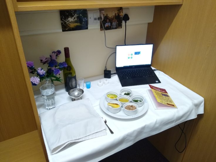 A small built-in desk is covered in a white tablecloth. There's some flowers, a plate with a set of small dishes.
