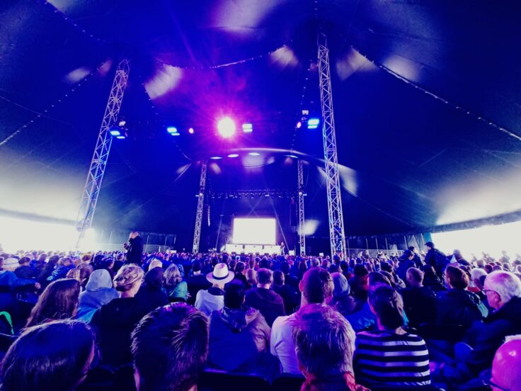 A group of people on a stage with a crowd watching