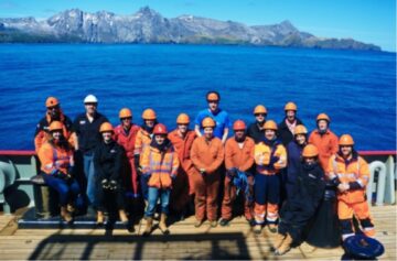 A group of people posing in front of water