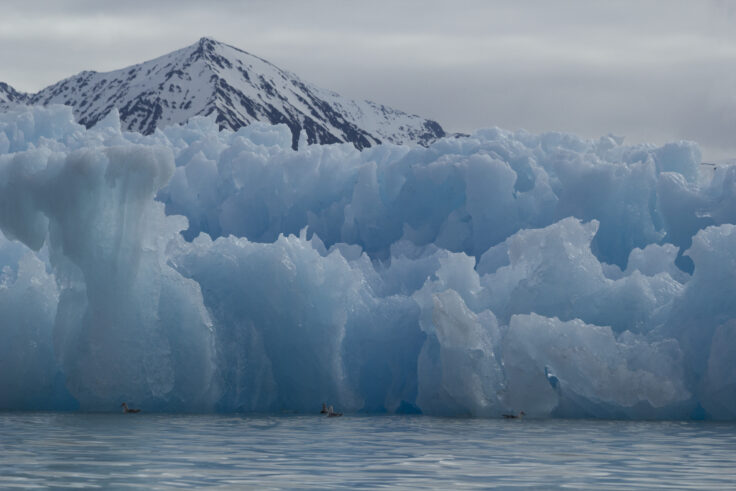 A wall of jagged ice in front of a mountain