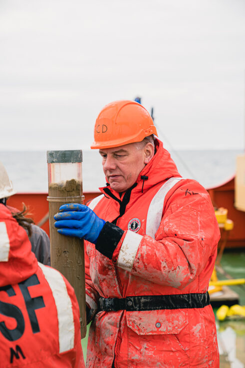 A man wearing protective clothing and hard hat with scientific equipment