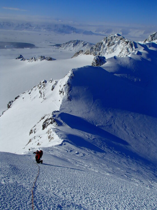 A man skiing down the side of a snow covered mountain