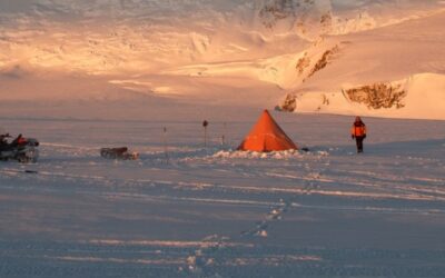 An Antarctic camp set up in front of a steep slope covered in ice