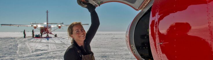 A person standing on ice opening an aircraft hatch