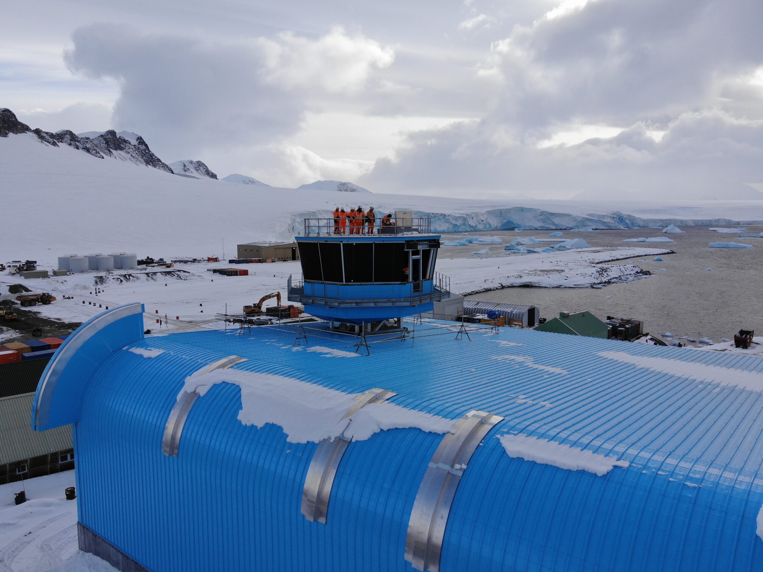 Operations tower on top of a bright blue building with snow on the top