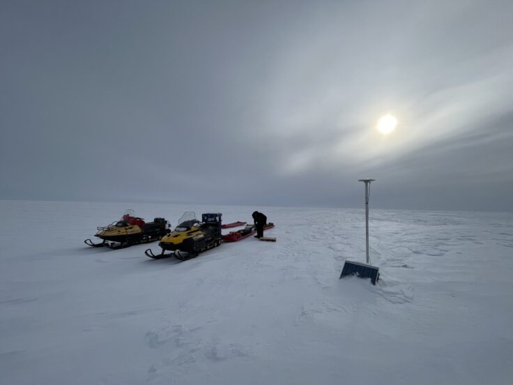 A group of people riding skis across snow covered ground