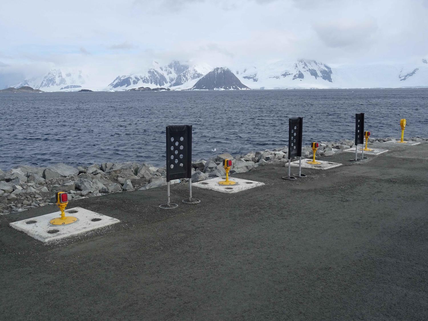 Lights fixed onto a runway with snowy mountains and icy sea in background.