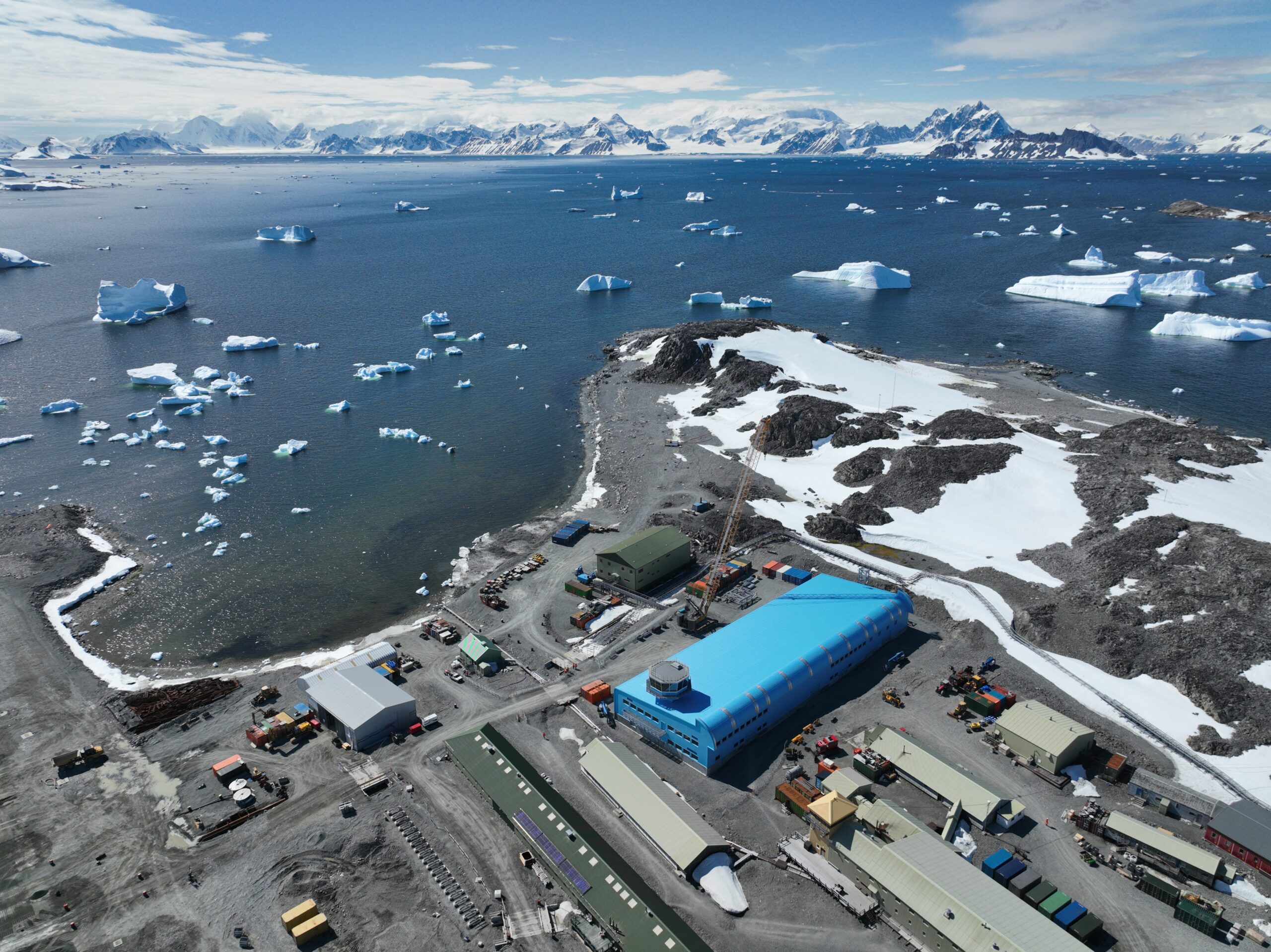 Aerial view looking down at a large blue building and a runway