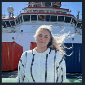 A person standing in front of a boat next to a body of water