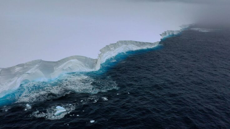 An aerial view of the edge of a large iceberg