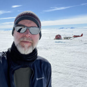 A man wearing a hat and sunglasses posing for the camera