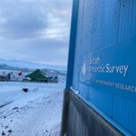 A sign on the side of a large building with snow on the ground around it