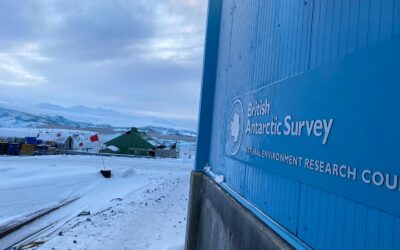 A sign on the side of a large building with snow on the ground around it