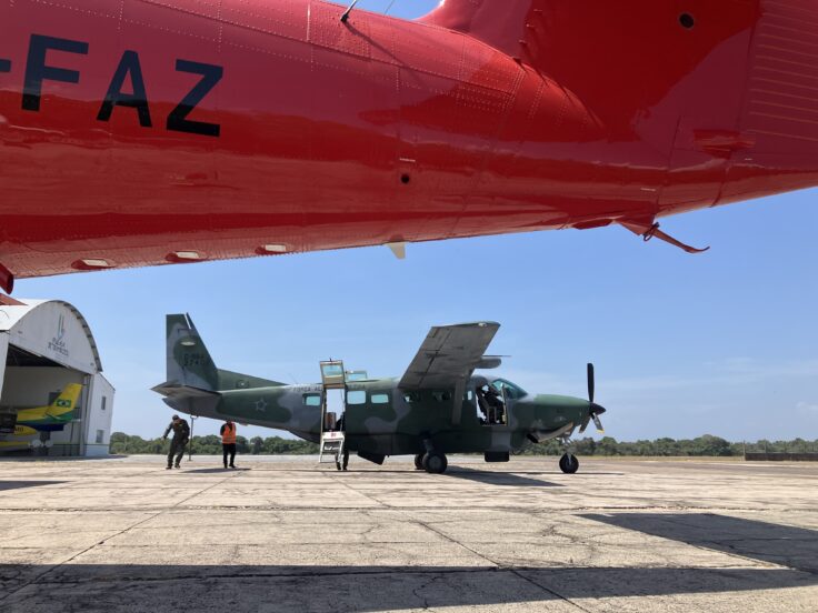 A red British Antarctic Survey aircraft in the foreground and a green Brazilian Air Force aircraft in the background.