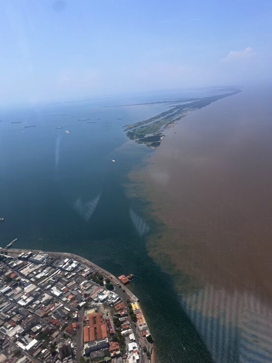 A view of two bodies of water running alongside each other. One is brown and the other is blue.