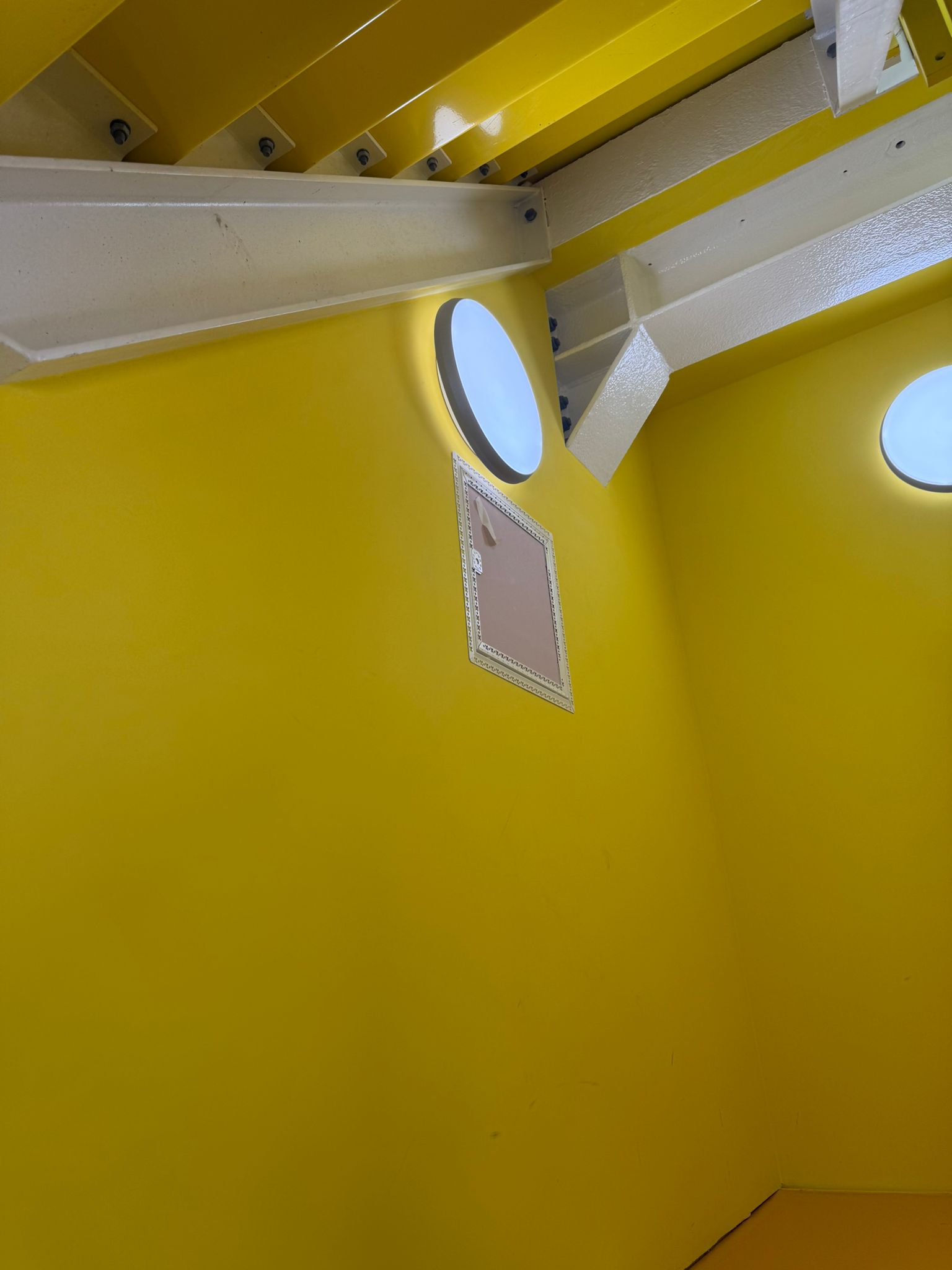 A round porthole light on the wall by a stairwell.