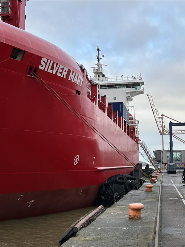 A large ship in the water beside a pier
