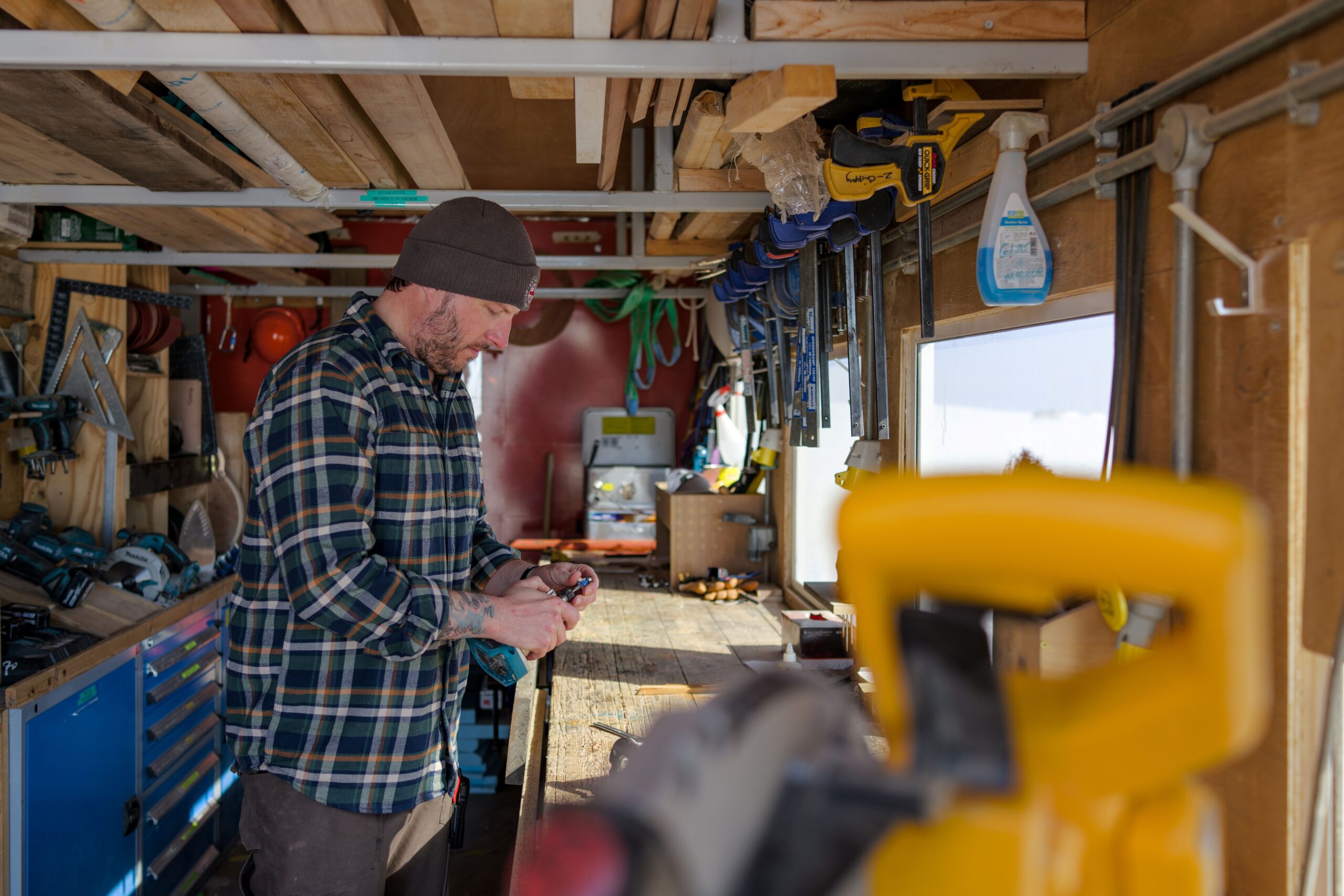 A man in a carpentry shed - snow is visible out the window
