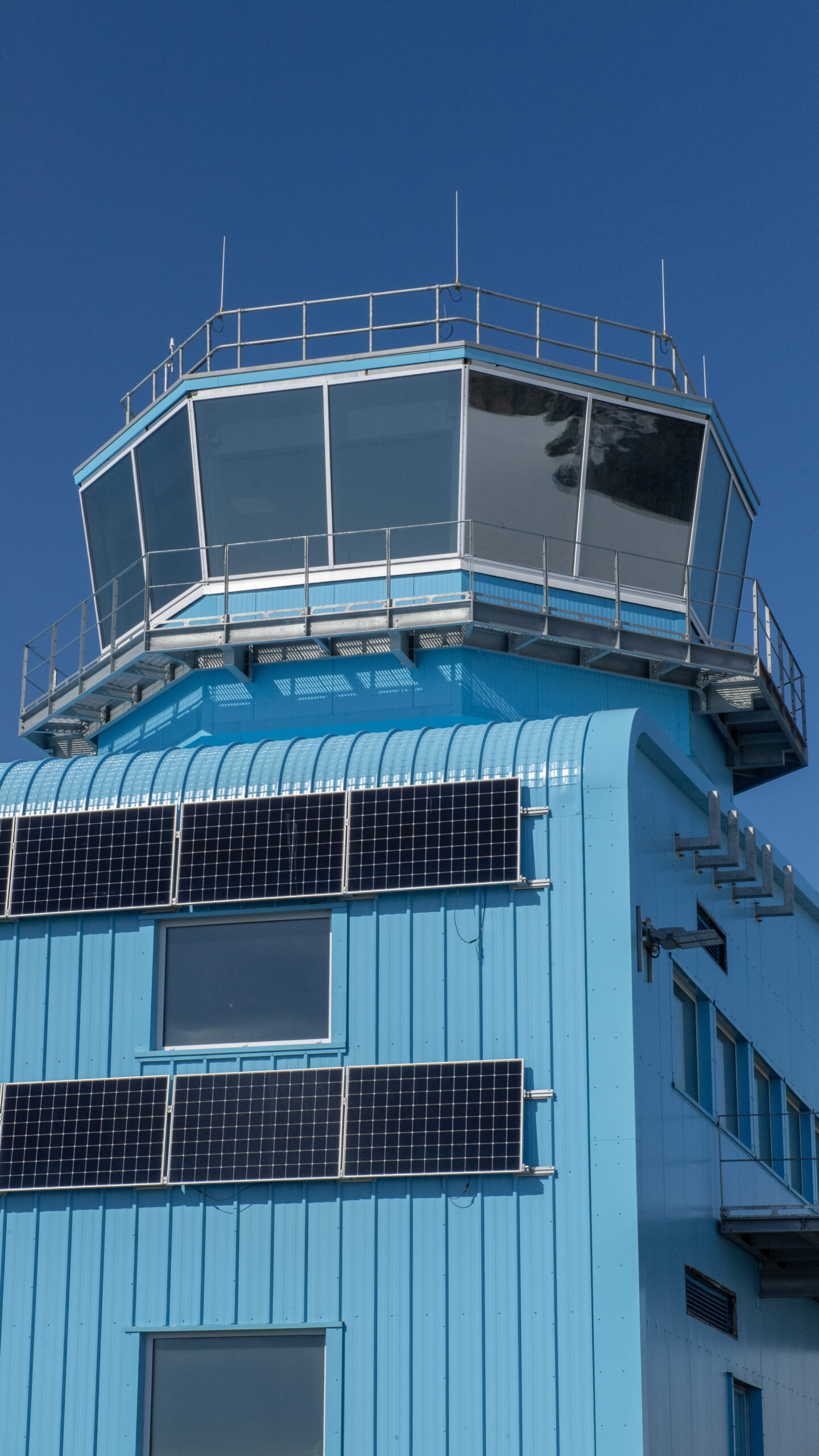 A tower on top of a large blue building with large windws.