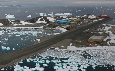 aerial view of an antarctic research station with a runway and a large blue building
