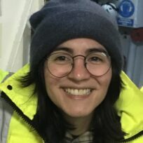 A woman wearing a hat and smiling at the camera