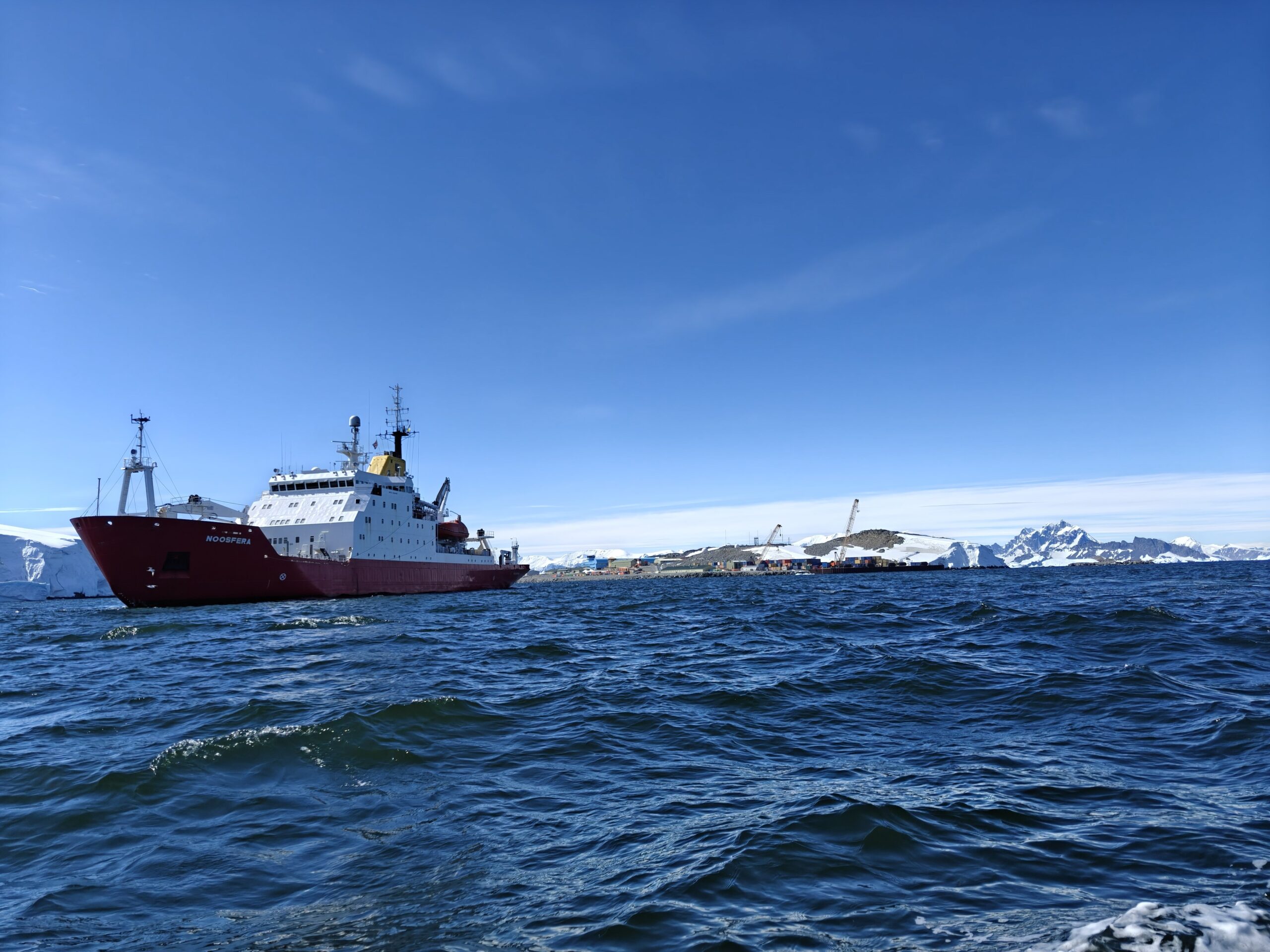 A large ship in a body of water with snow covered mountains in the background