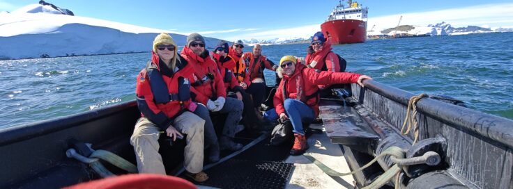 A group of people sitting on a boat next to a body of water