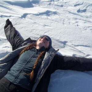 A man lying on top of a snow covered slope