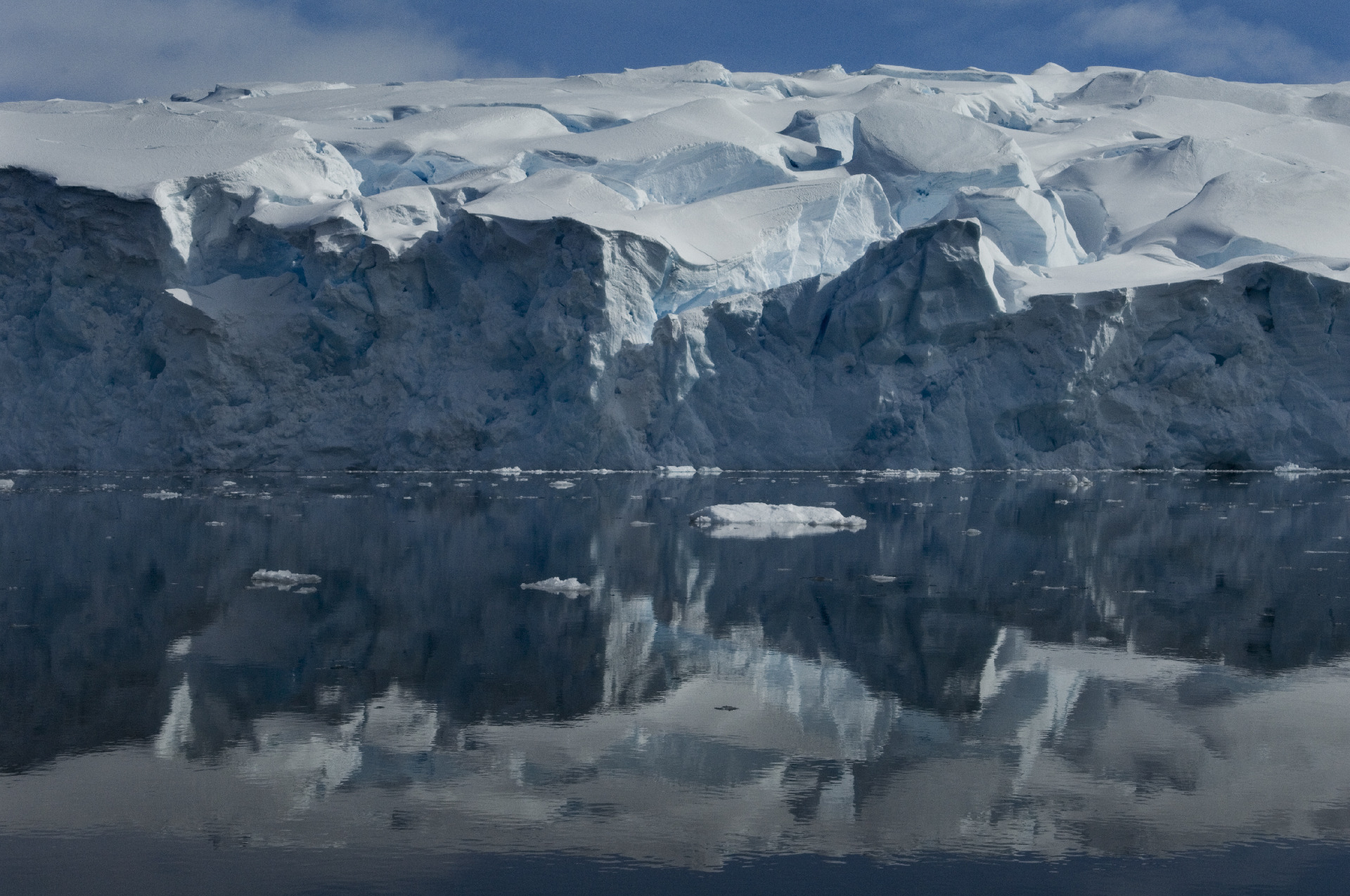 A view of a snow covered mountain and ice covered waters in front